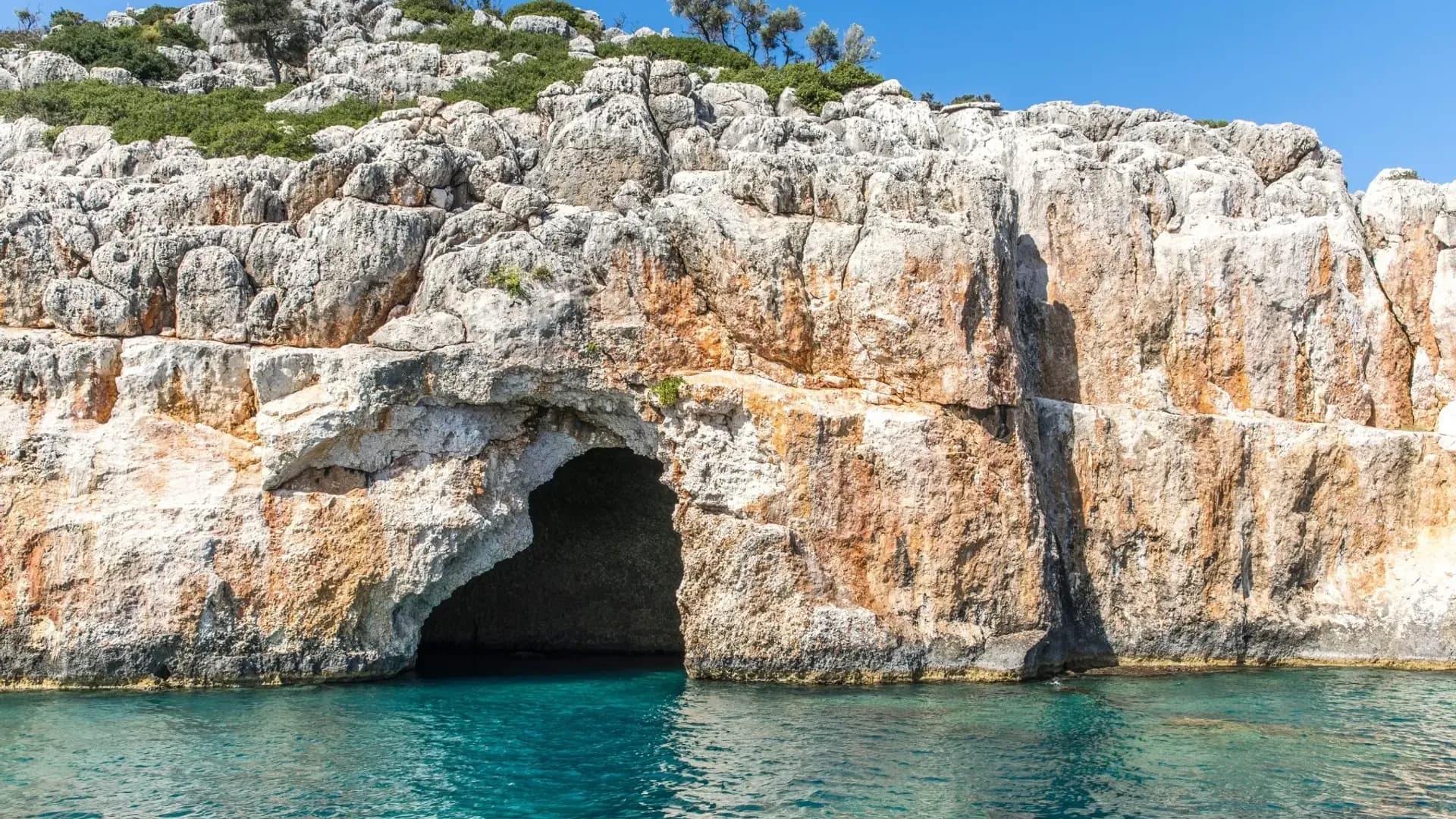 Felsige Meereshöhle neben klarem, blauem Wasser