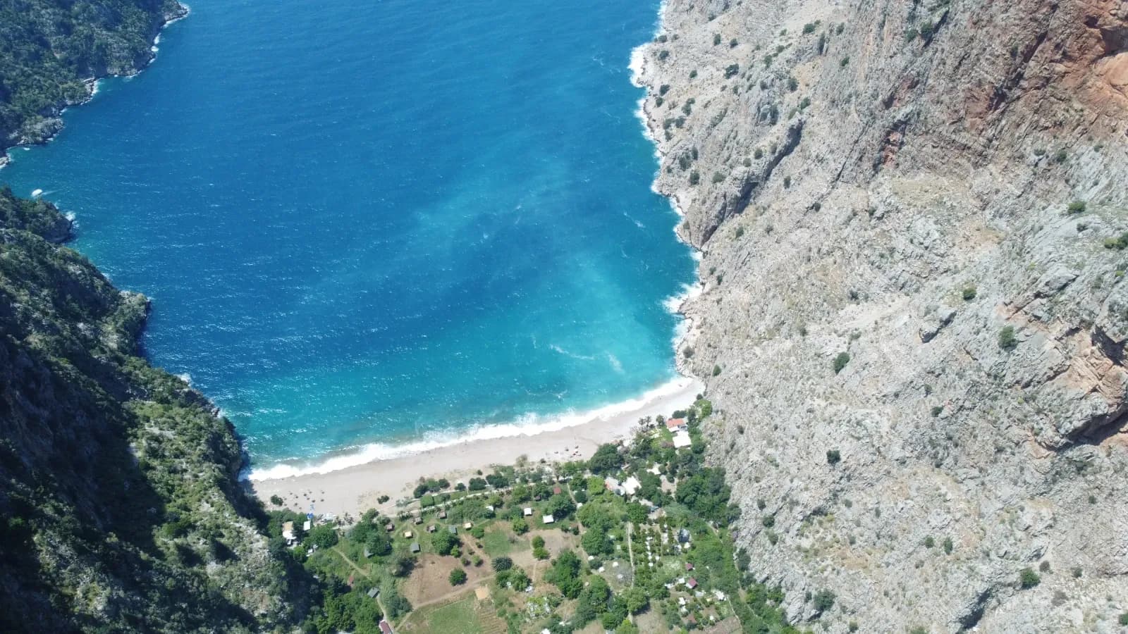 Strand an der Mündung eines steilen felsigen Tals