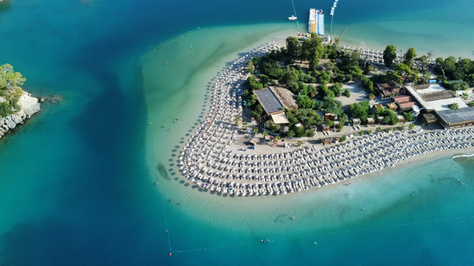 Luftaufnahme eines geschwungenen Strandes neben einer Lagune
