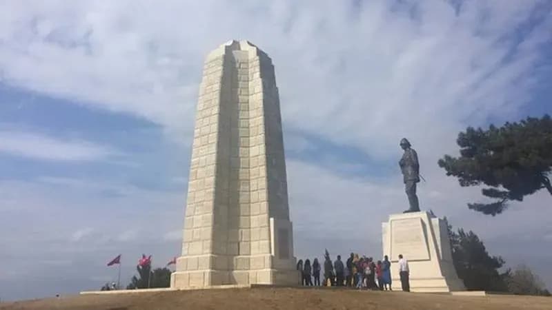 Высокий каменный обелиск рядом с бронзовой статуей