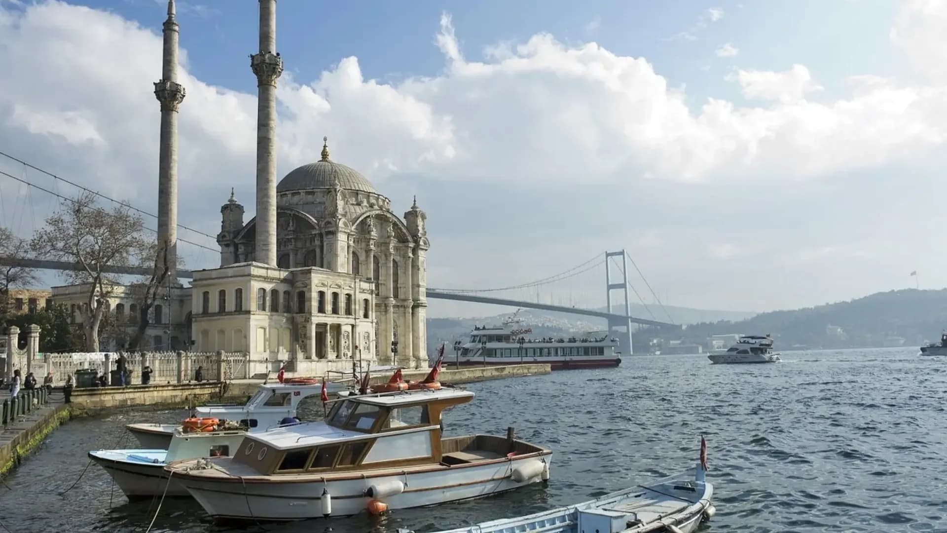 Moschee am Wasser und Boote unter einer Hängebrücke