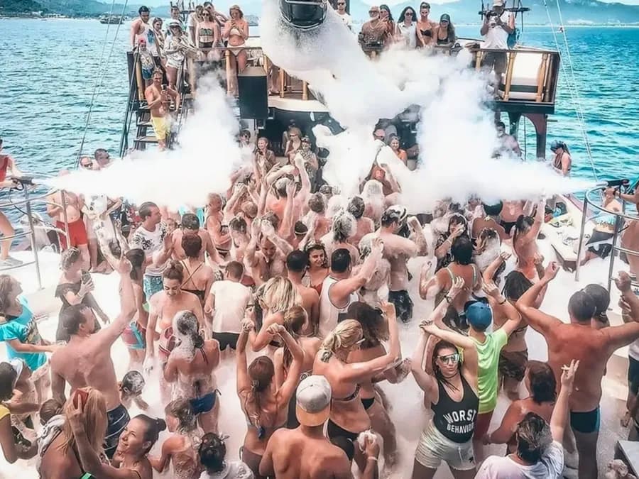 Guests dancing at a foam party on a boat deck