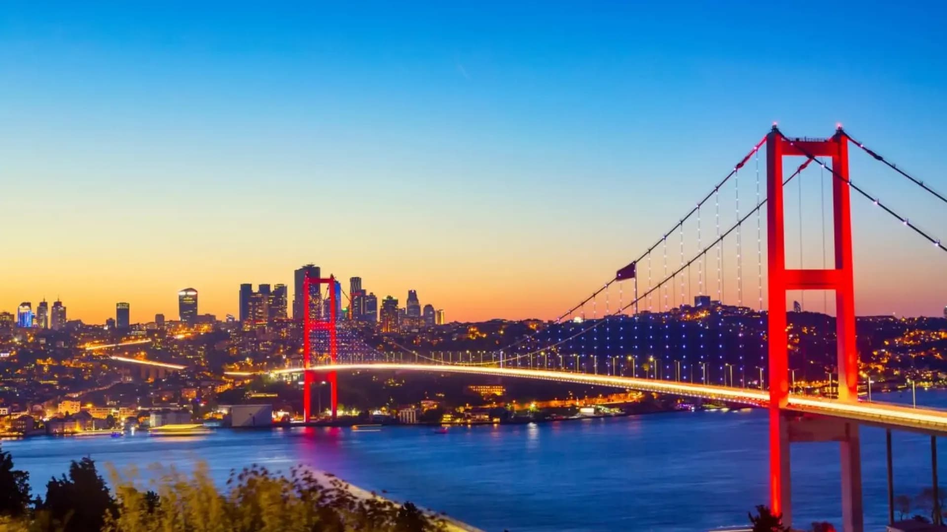Illuminated suspension bridge above a city at sunset