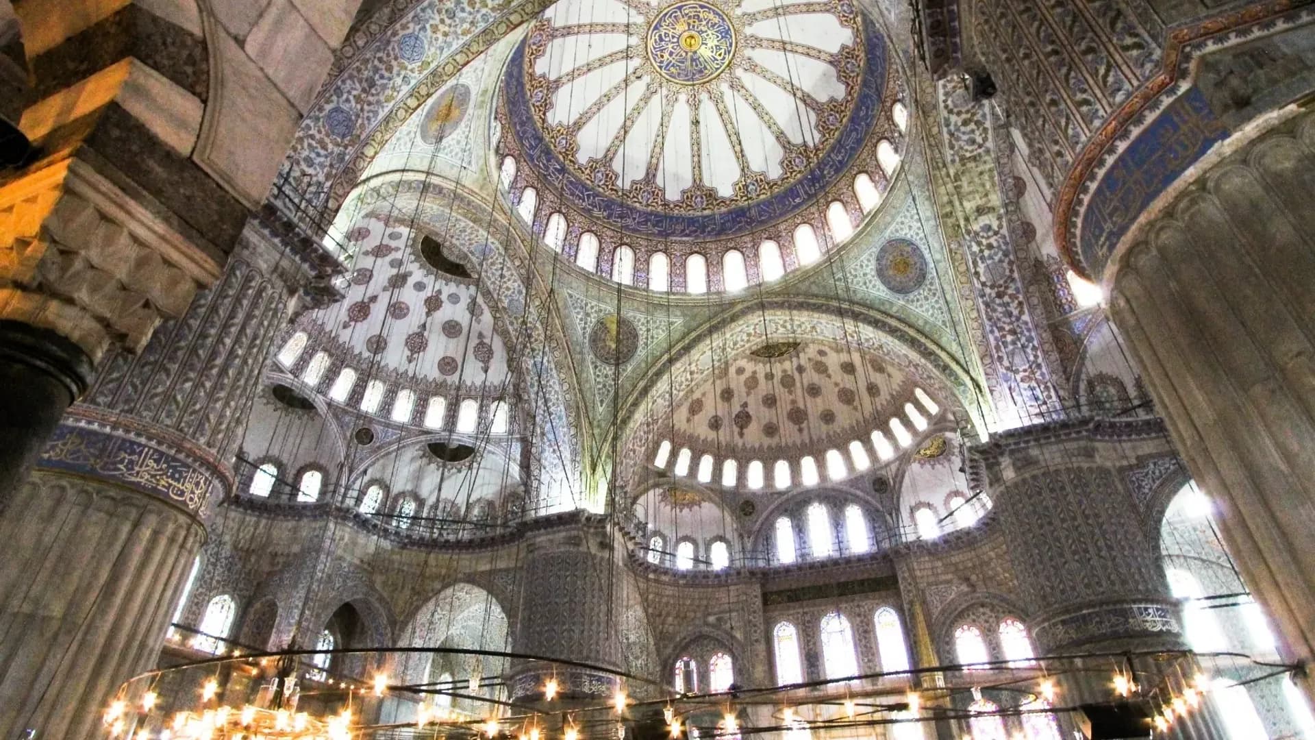 Büyük bir avizenin altındaki süslü cami tavanı