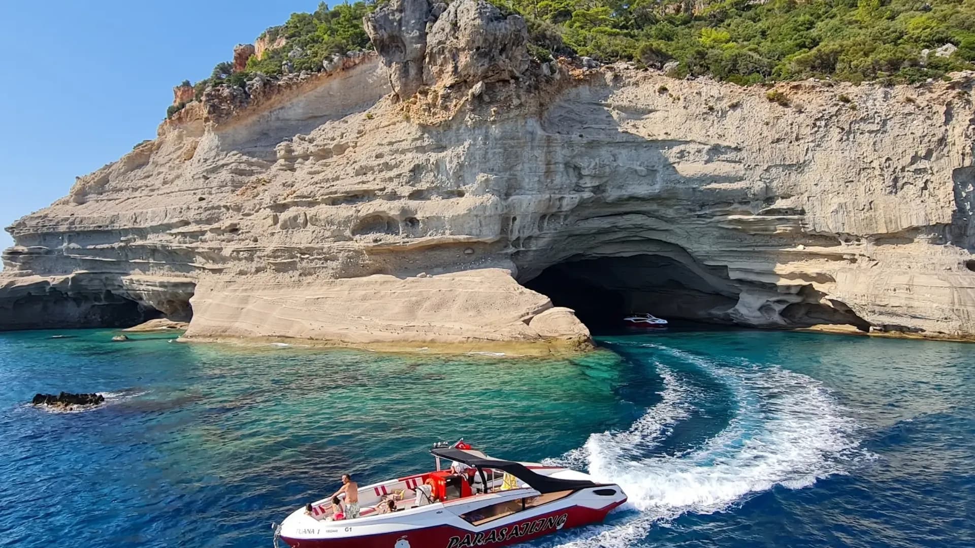 Red speedboat beside pale coastal cliffs