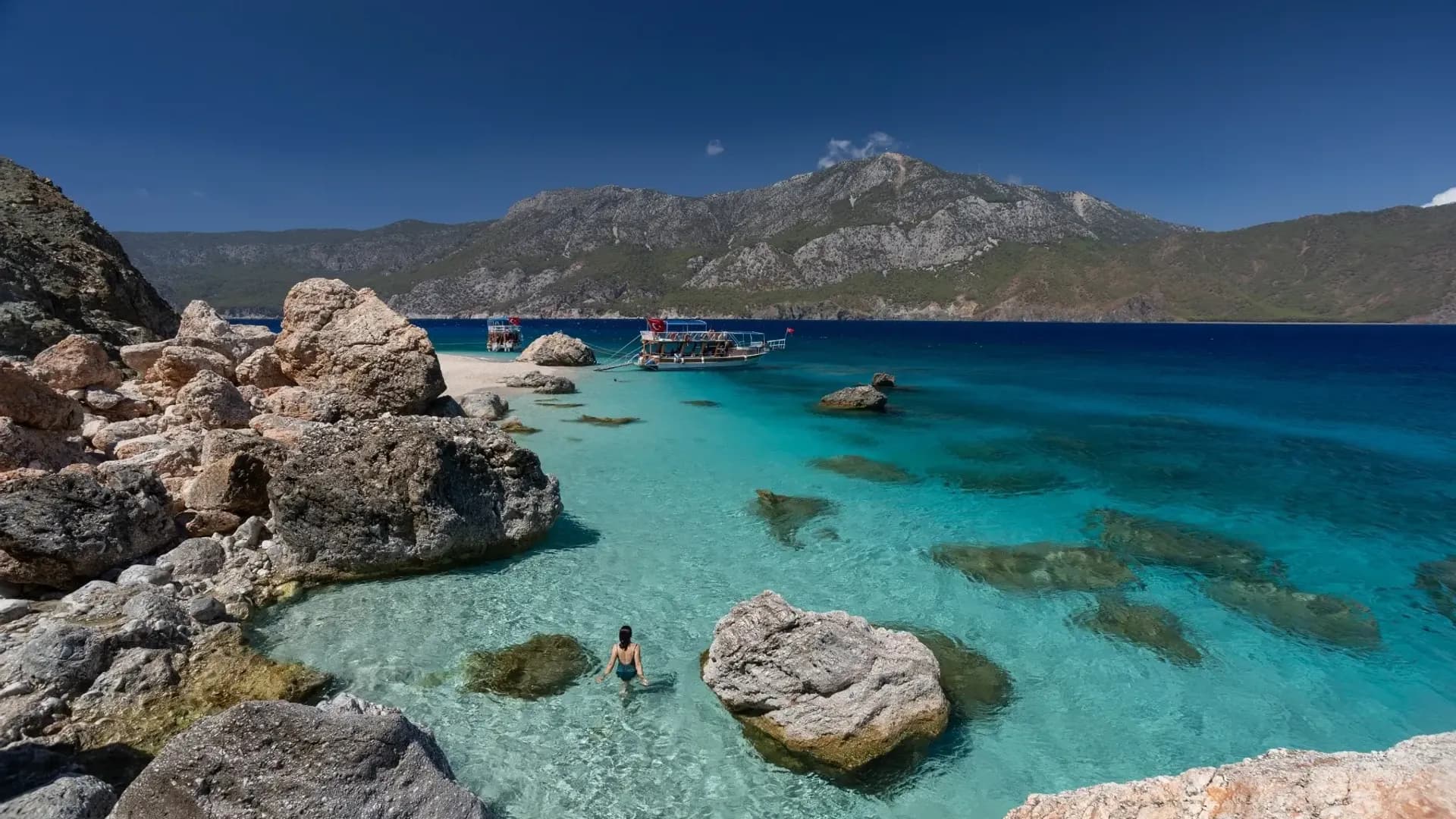 Visitors beside rocks on a turquoise shore