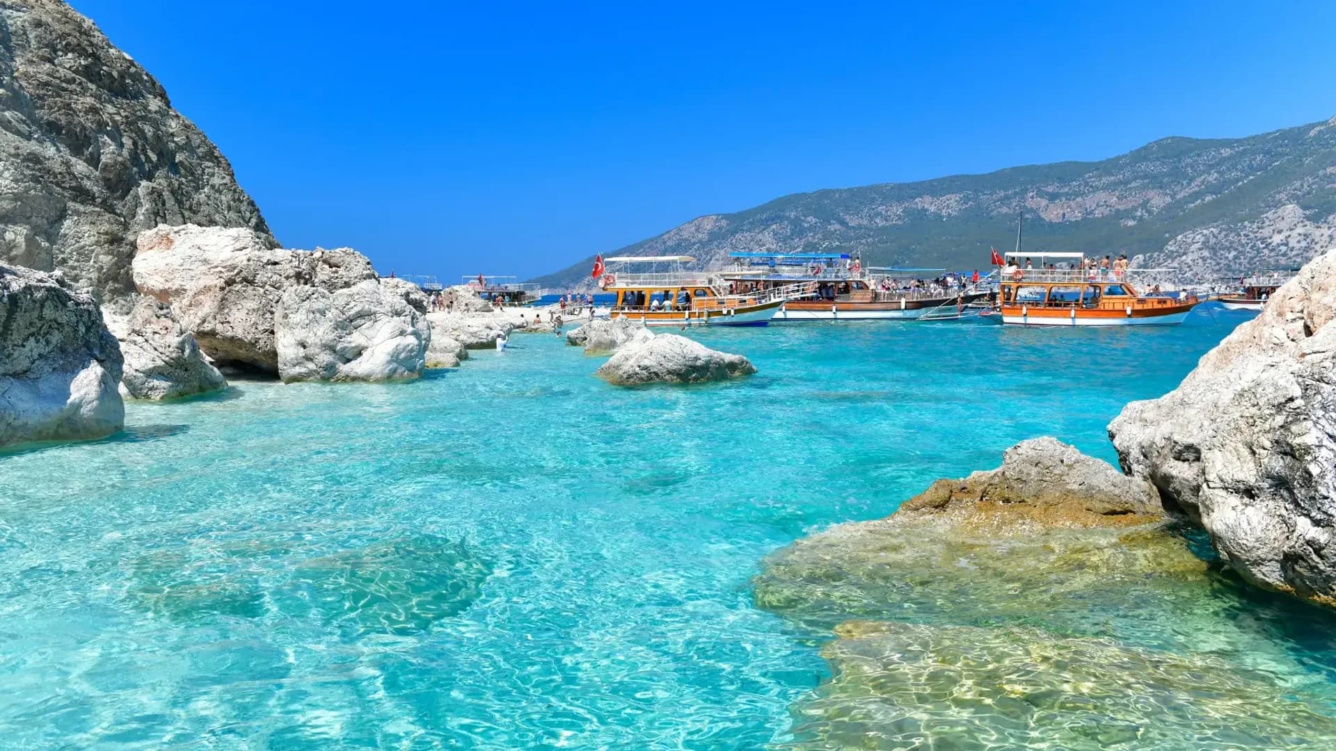 Boats beyond clear turquoise water and pale rocks