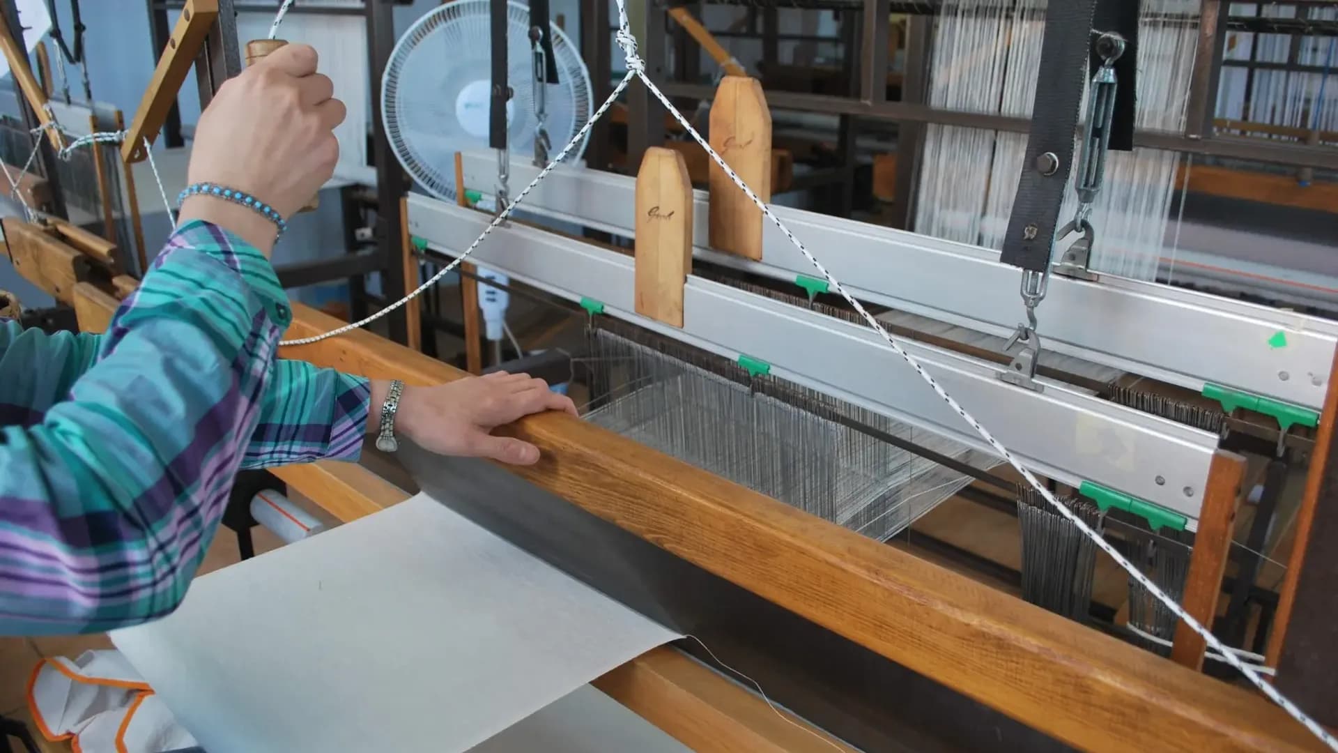 Hands working at a weaving loom