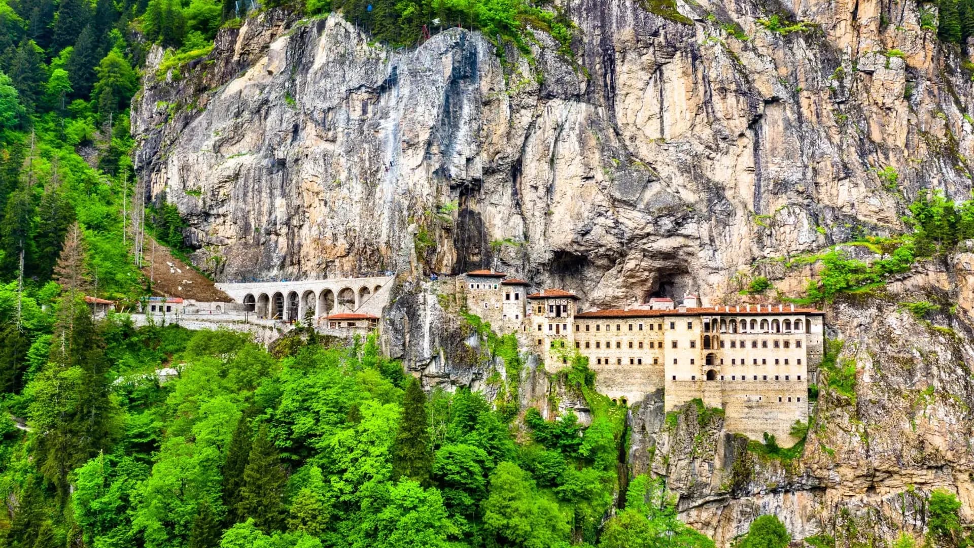 Monastery buildings beneath a steep rock face