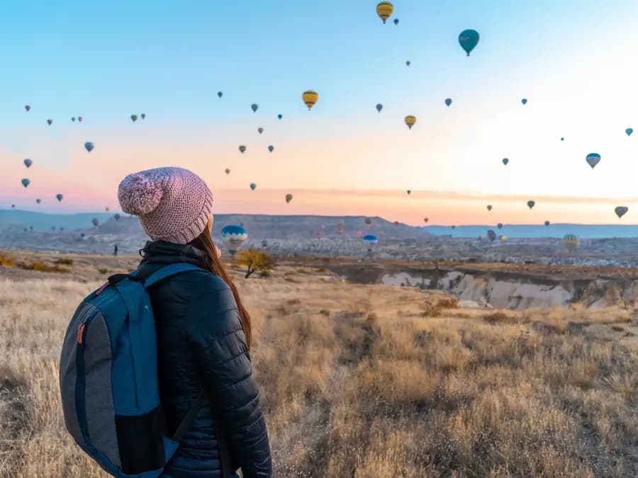 Besucher beobachten Heißluftballons über einem Tal