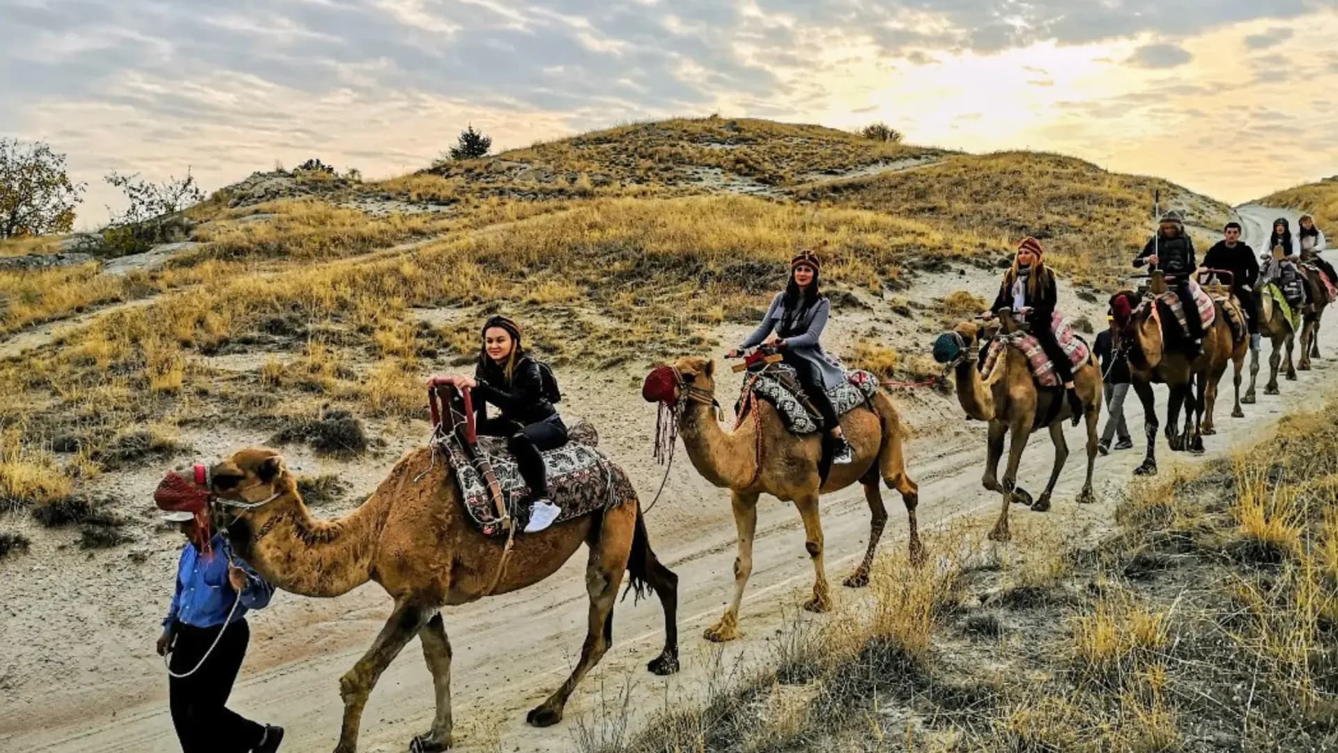Camel riders crossing a grassy hillside