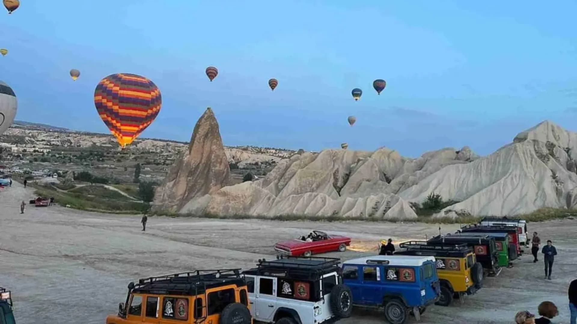 Vehicles beside a rocky landscape and balloons