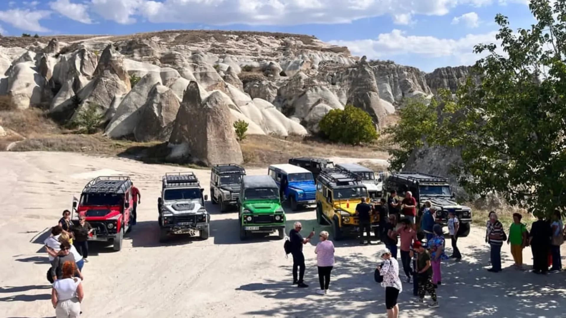 Visitors and off-road vehicles beside hills
