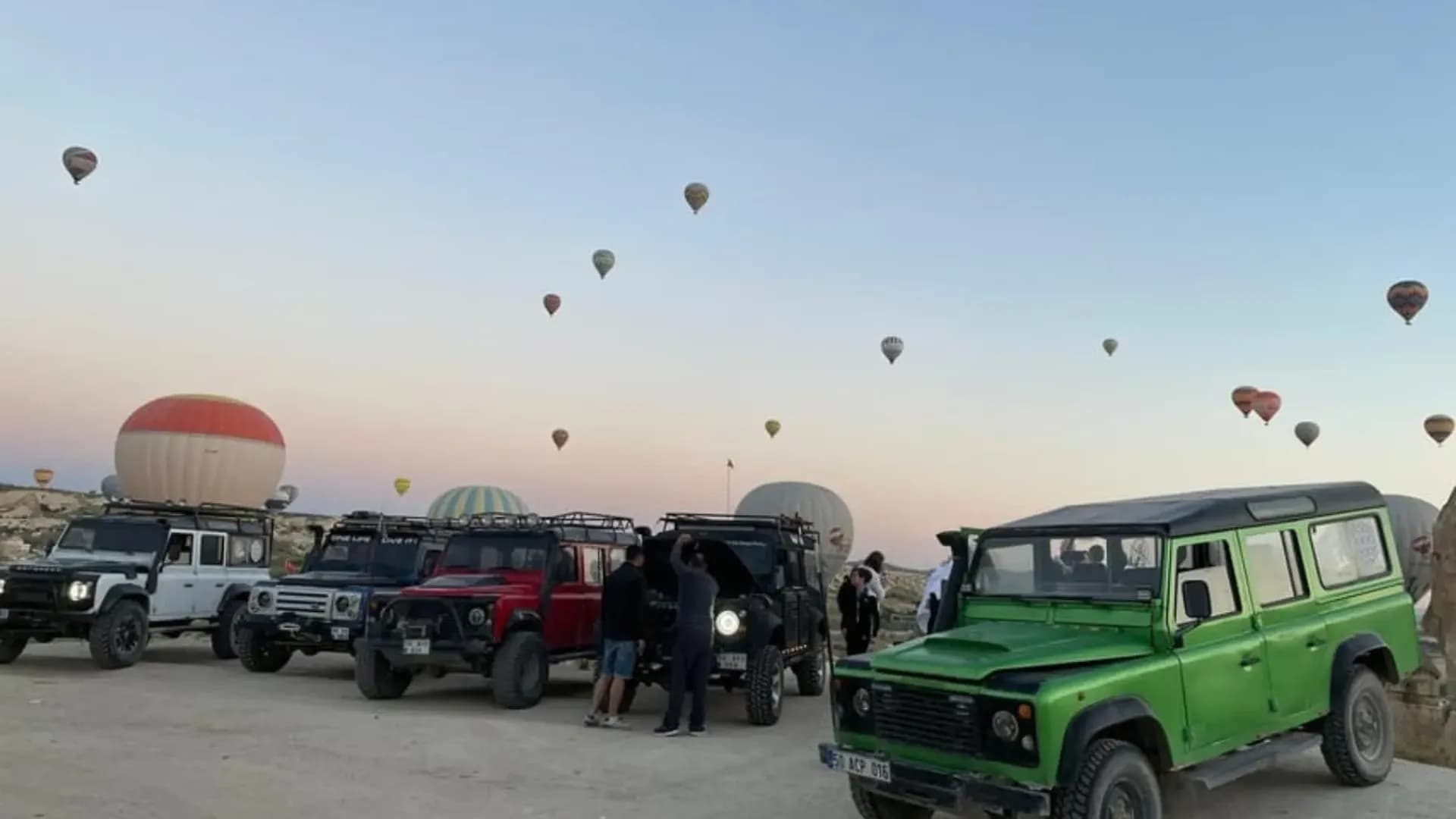 Off-road vehicles beside balloons at sunrise