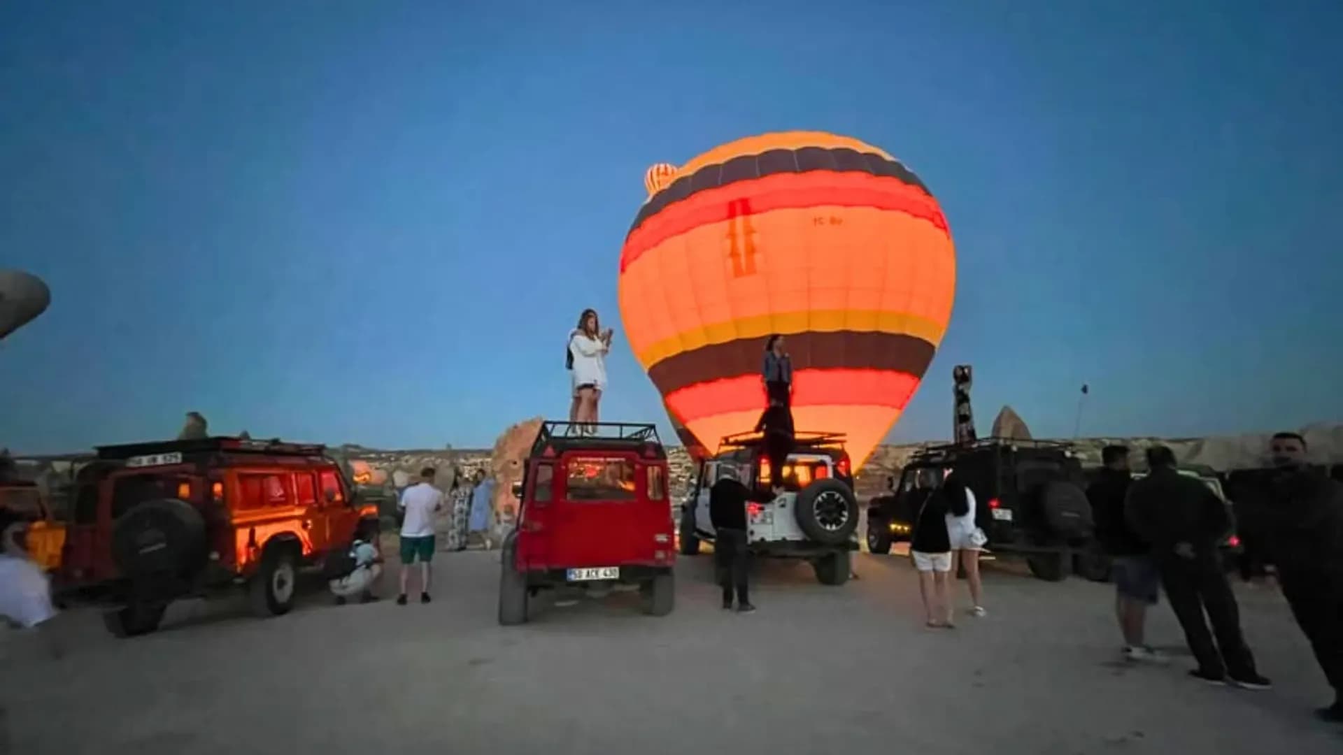 Visitors and vehicles near an illuminated balloon