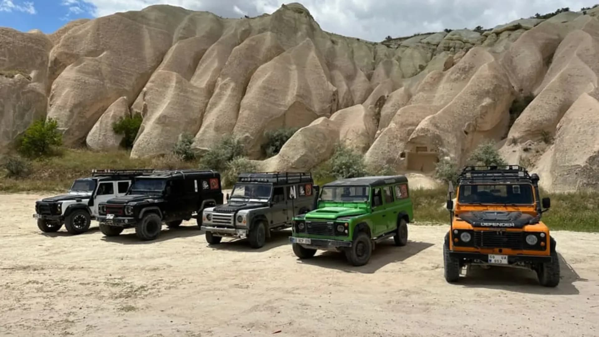 Off-road vehicles beside a rocky hillside