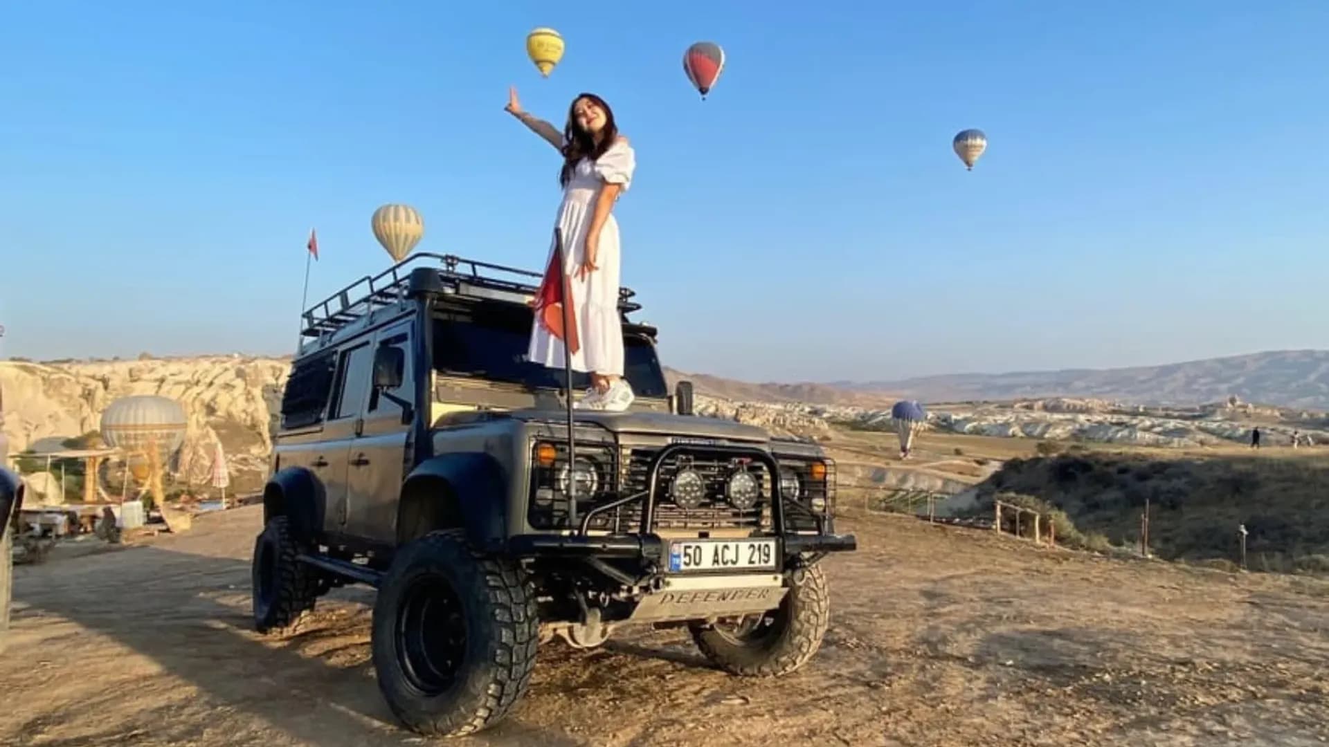 Person standing on an off-road vehicle with balloons behind