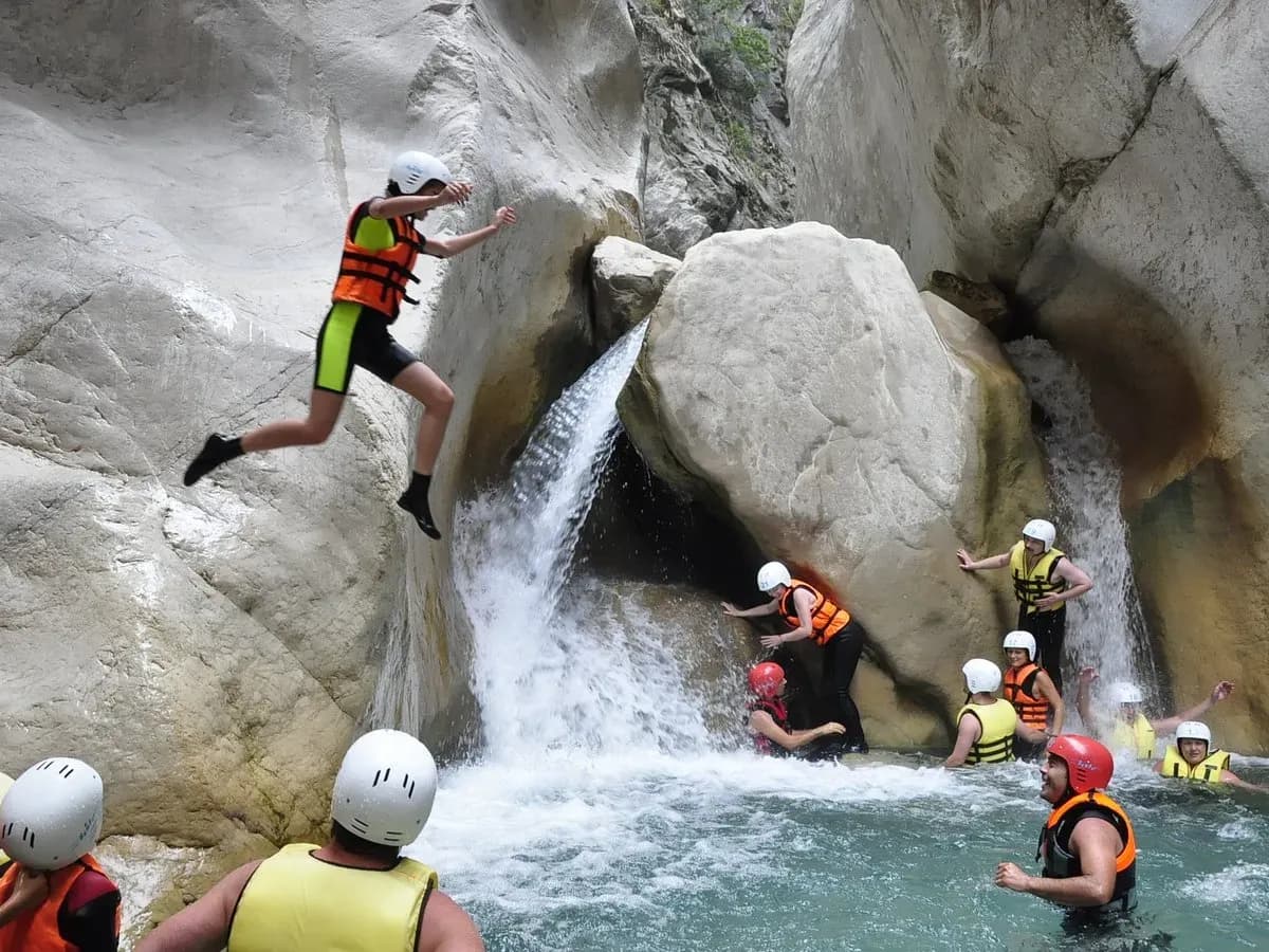 Behelmter Besucher springt neben einem Wasserfall