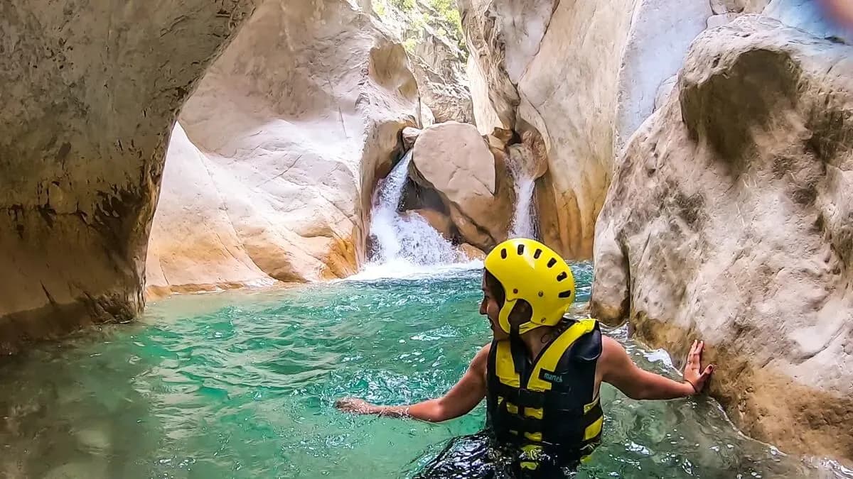 Behelmter Besucher watet durch das Wasser der Schlucht