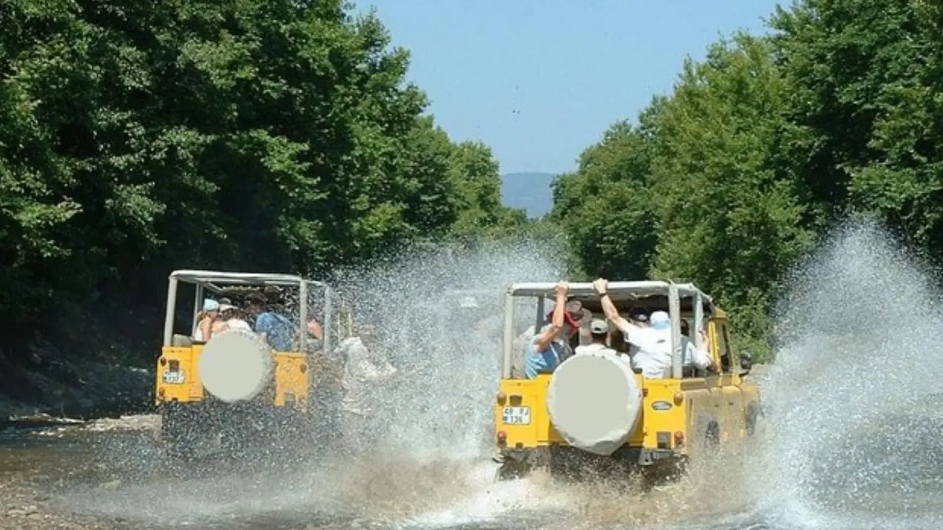 Gelbe Jeeps fahren durch seichtes Wasser