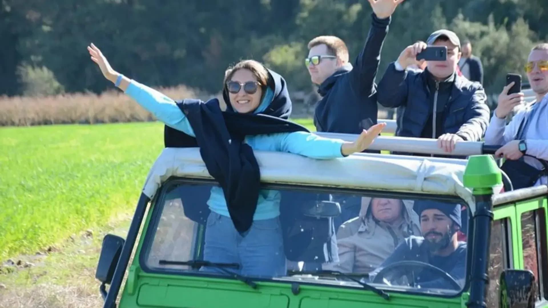 Passagiere in einem offenen grünen Jeep