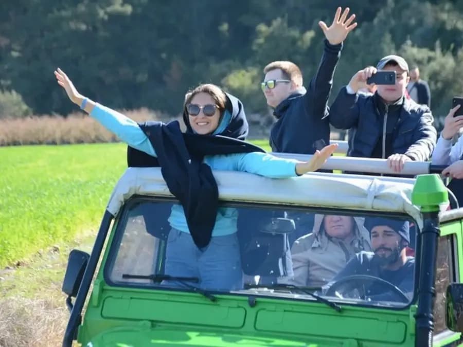 Passagiere in einem offenen grünen Jeep