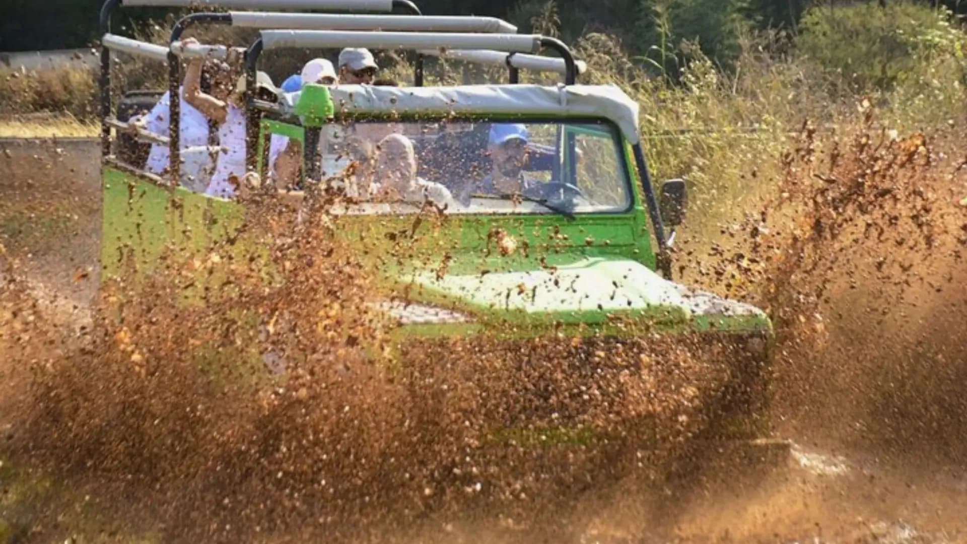 Grüner Jeep fährt durch schlammiges Wasser