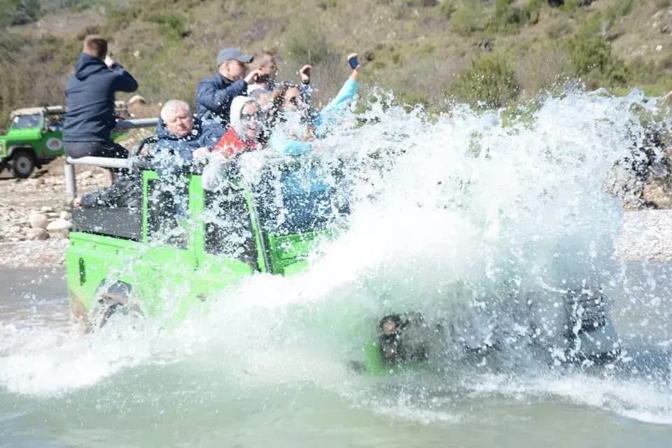 Passagiere in einem Jeep planschen durch Wasser
