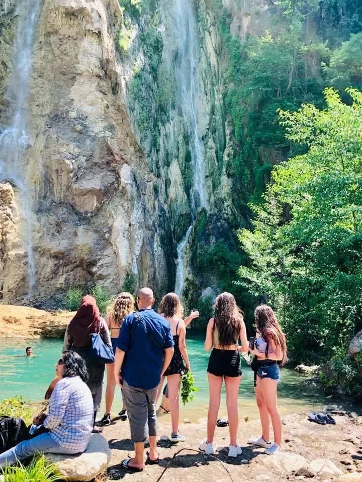 Besucher stehen neben einem Wasserfall