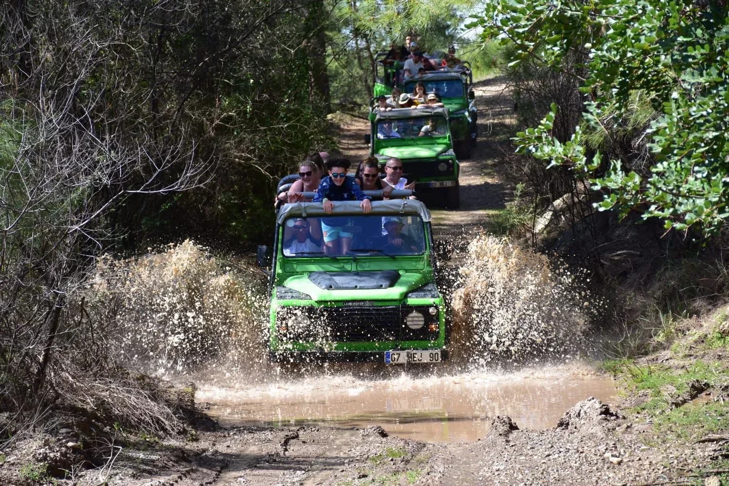 Jeep planscht auf einem bewaldeten Weg durch Wasser