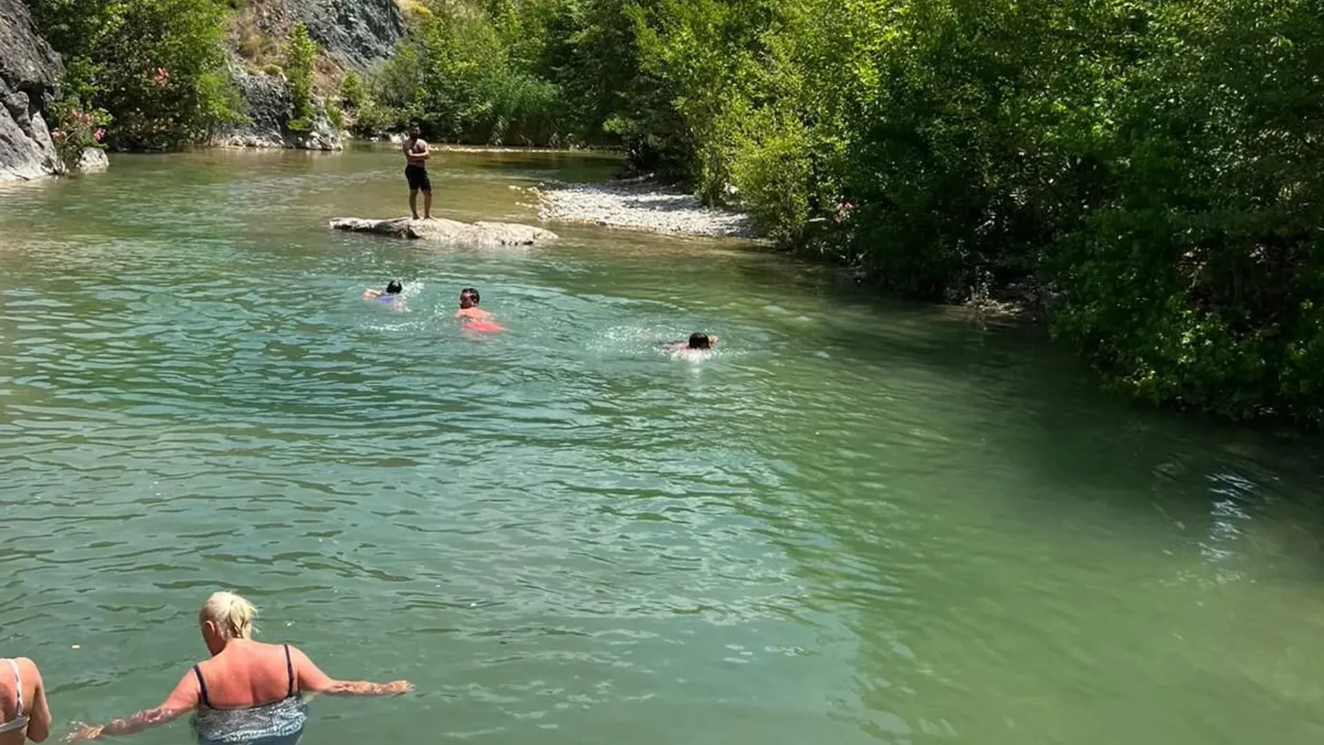 Besucher schwimmen in einem Flussbecken