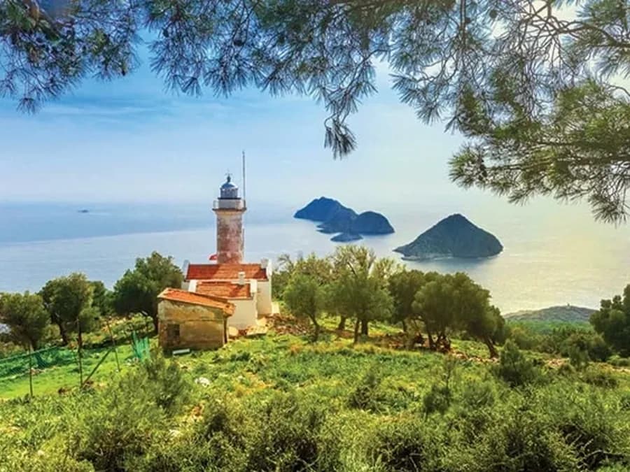 Denizin üstündeki yeşil bir burundaki deniz feneri