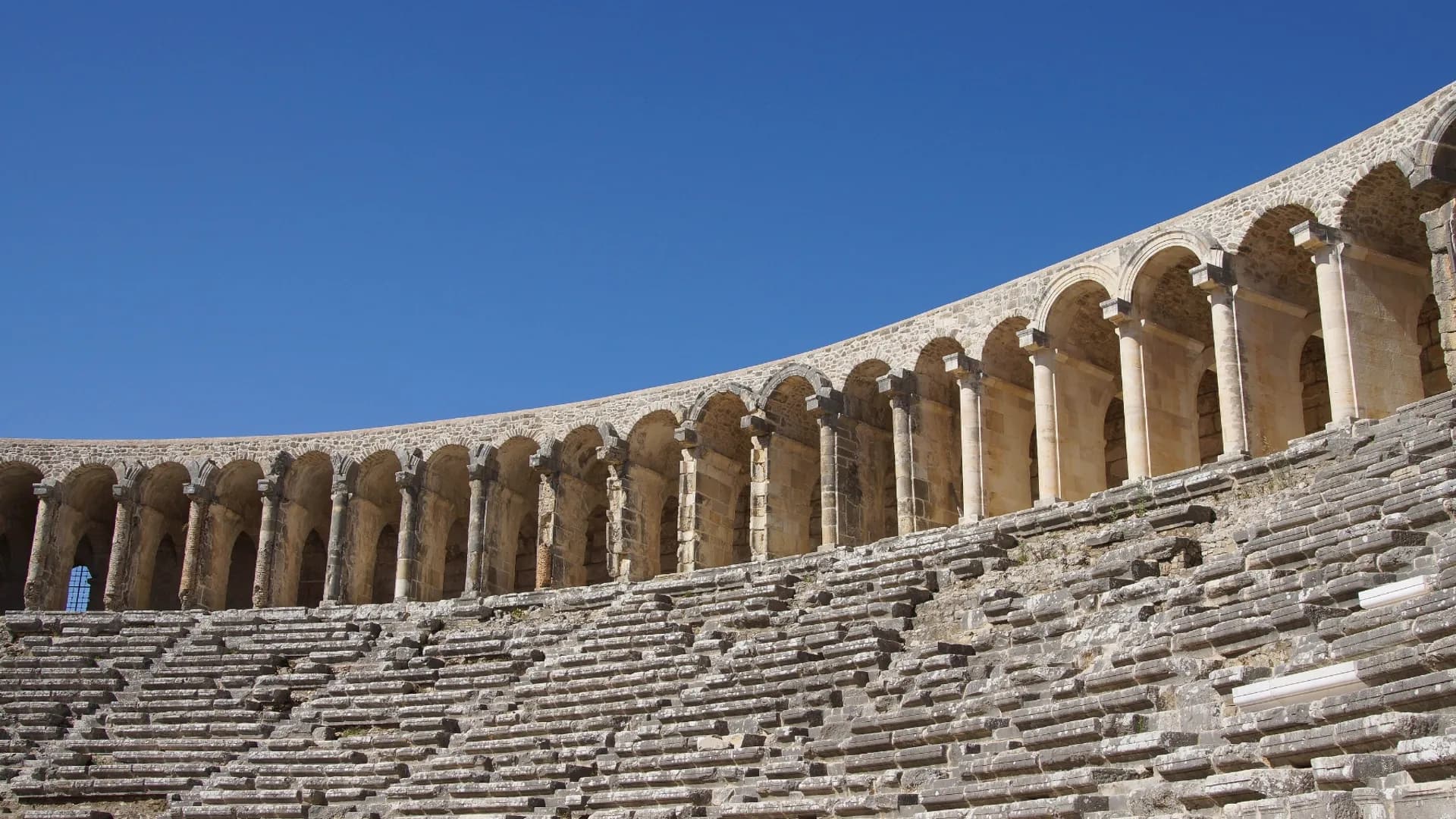 Rows of stone theatre seats beneath an arched gallery