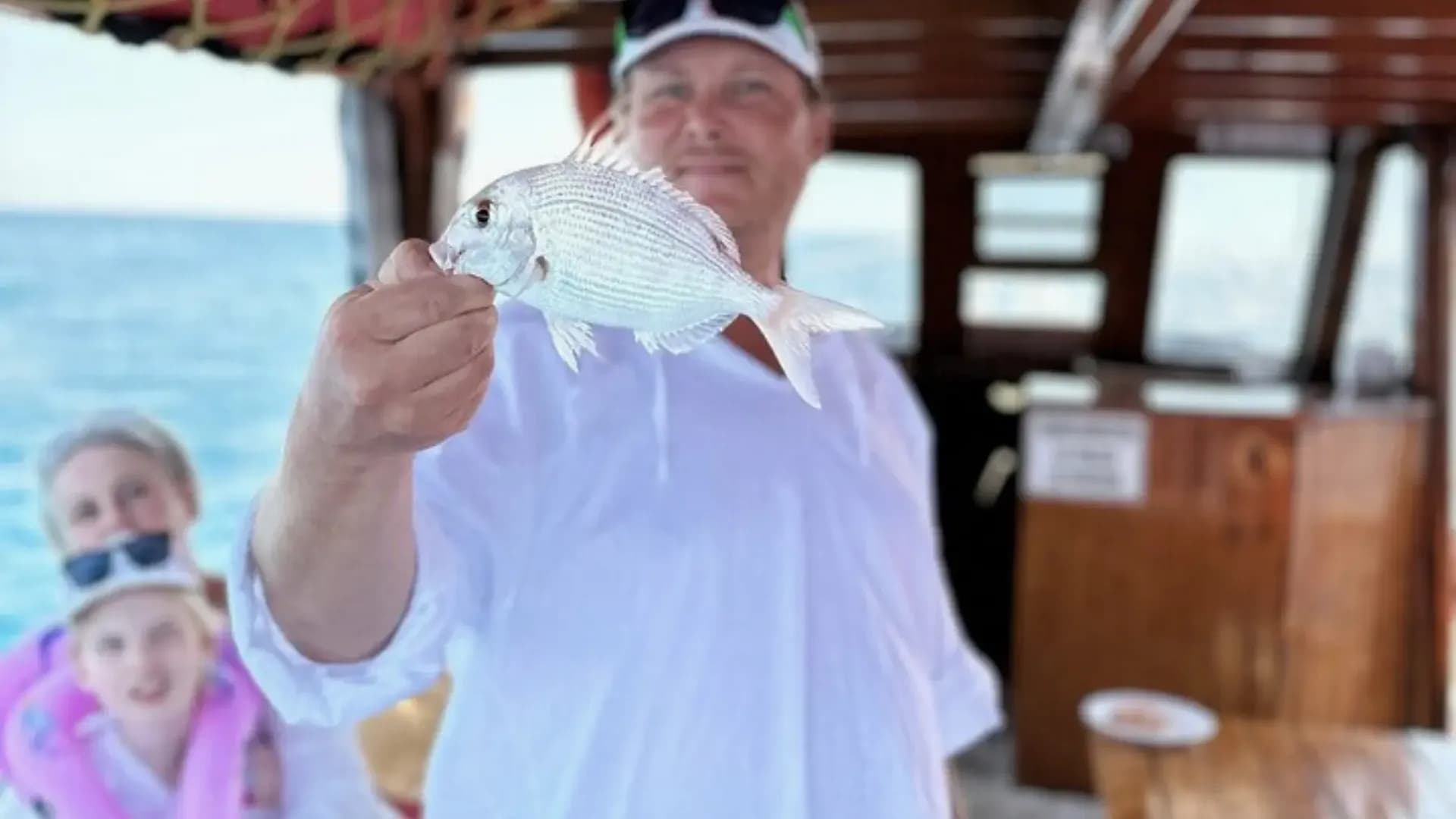 Visitor holding a fish on a boat