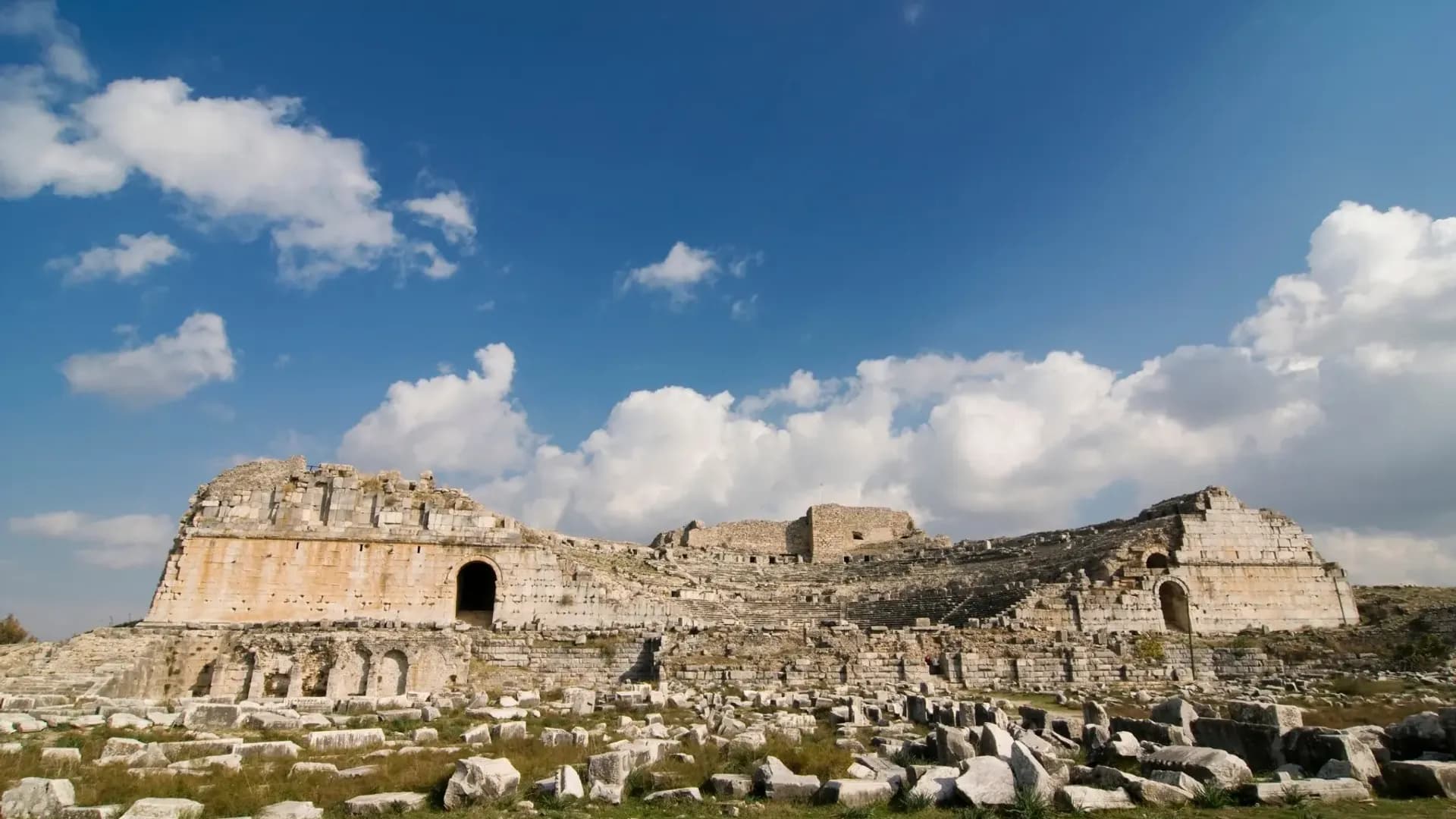 Ancient stone theatre ruins beneath clouds