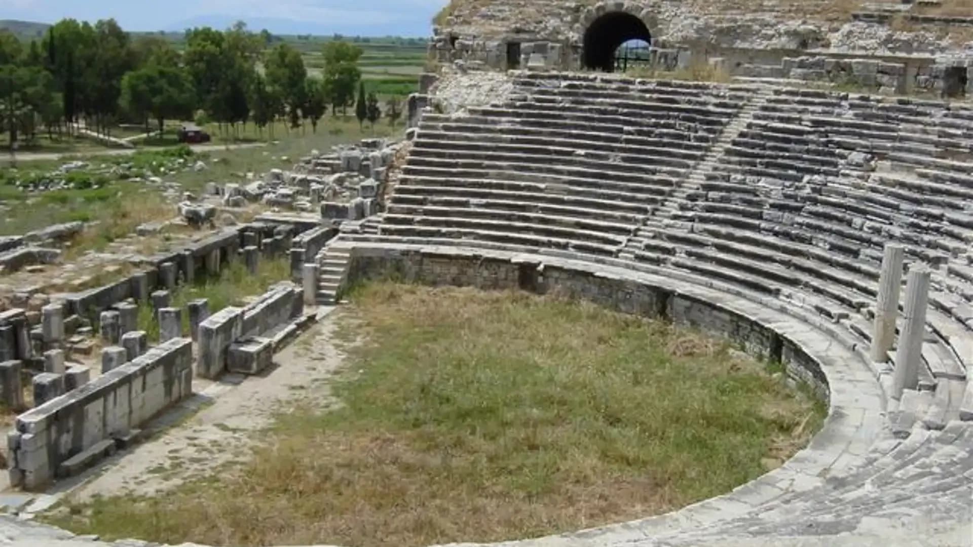 Ancient theatre and stone ruins beneath a hill