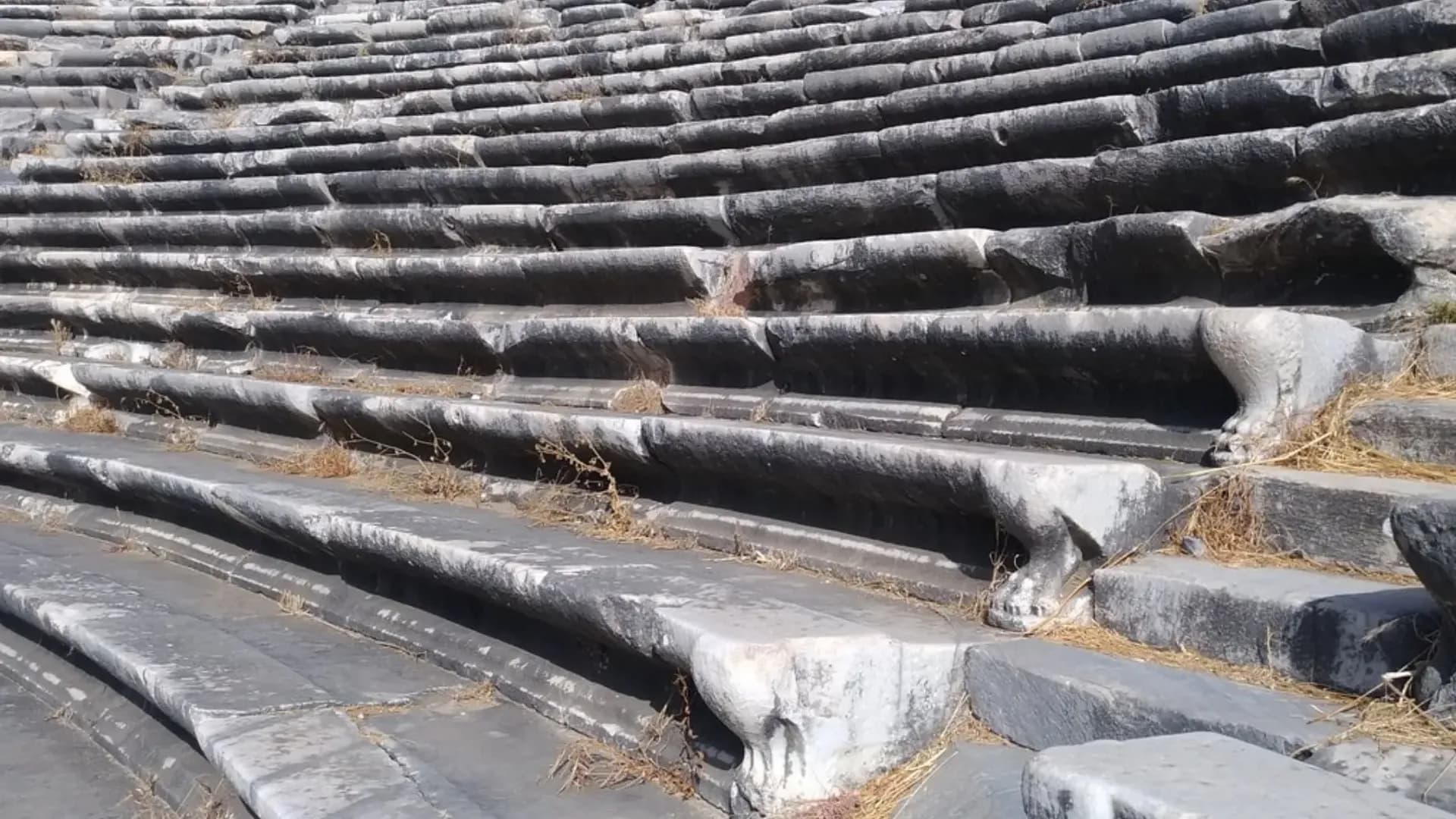 Worn rows of dark stone theatre seats