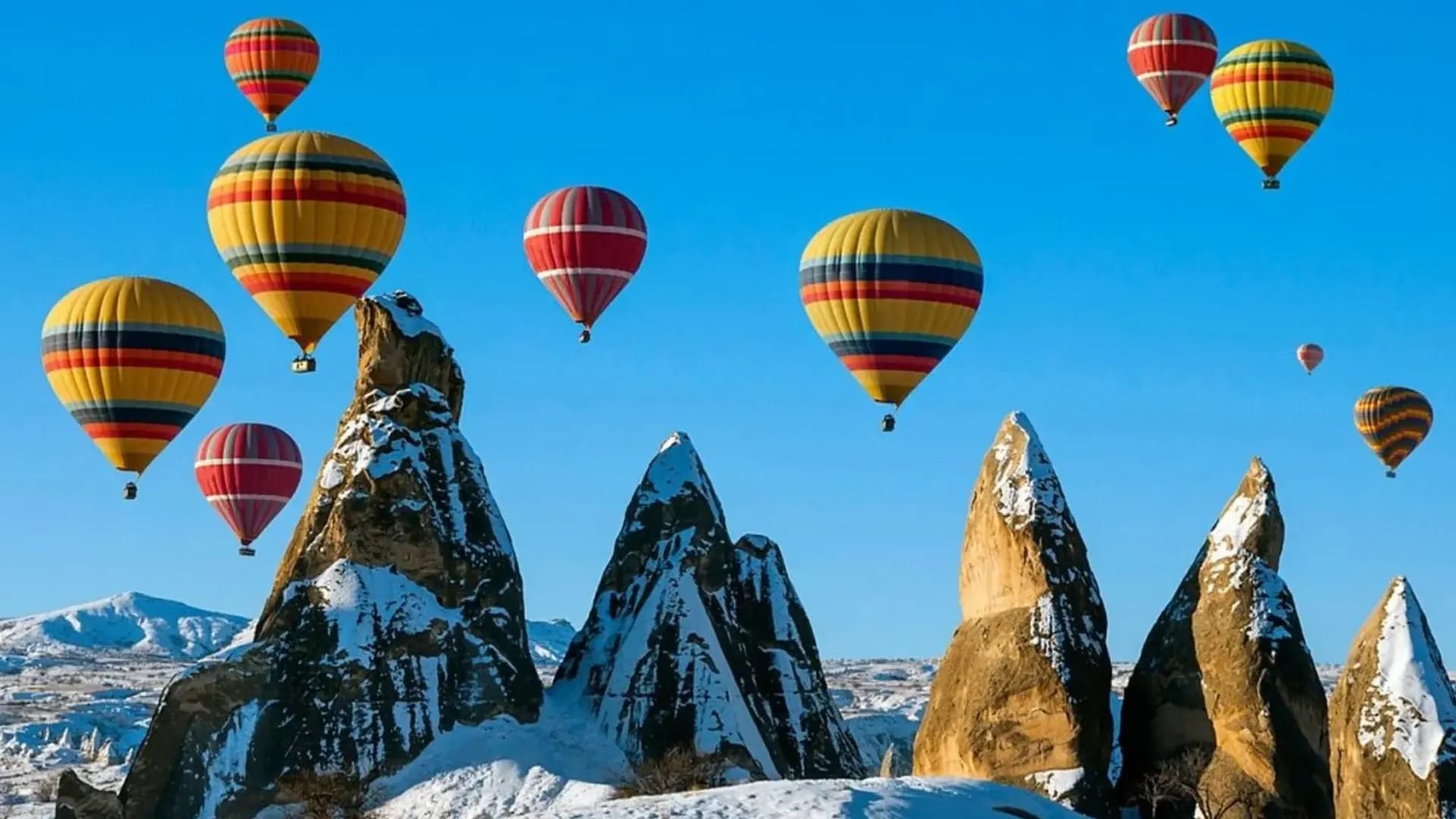 Heißluftballons über schneebedeckten Felsnadeln