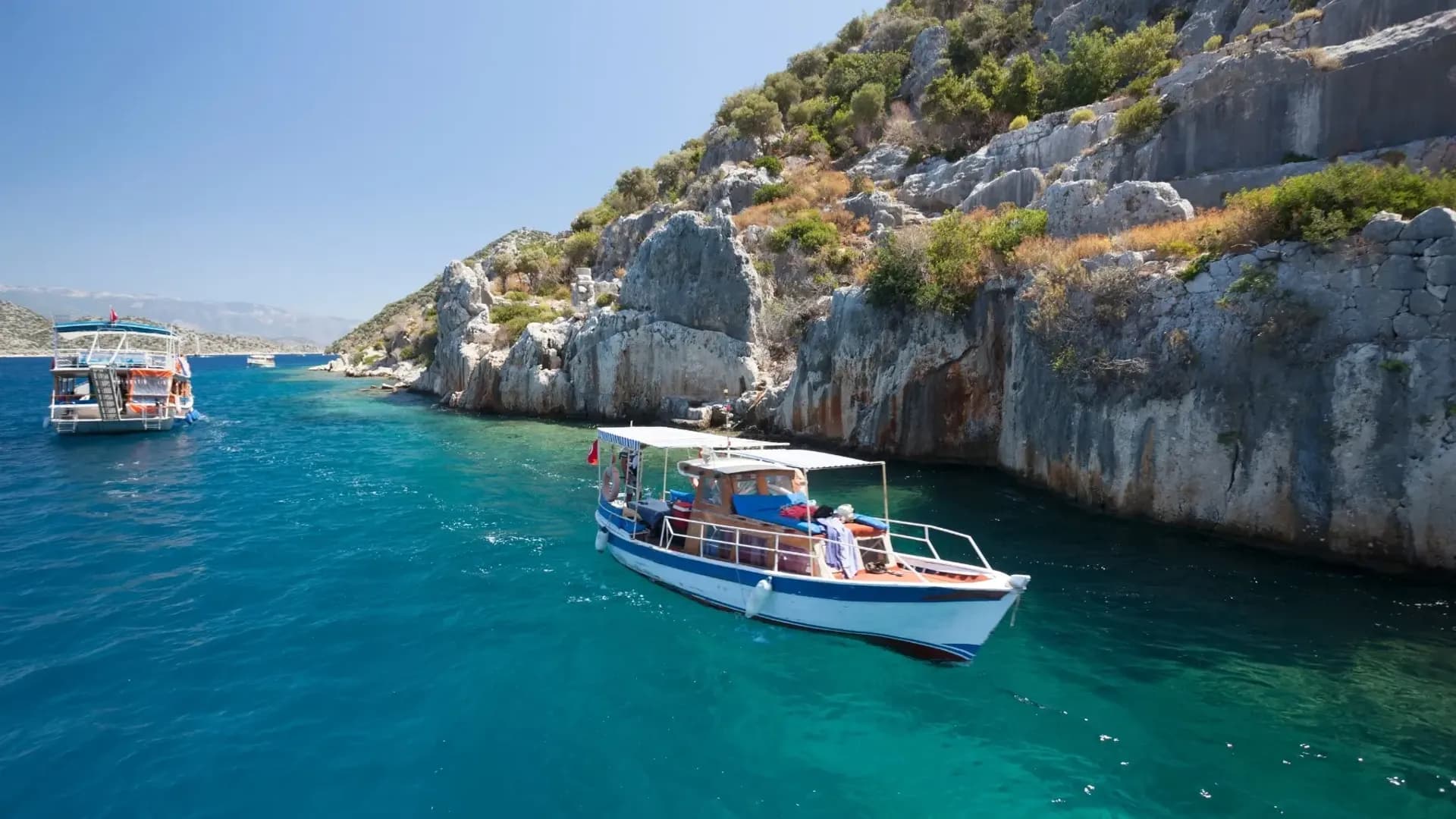 Boote neben hellen Felsklippen und klarem, blauem Wasser