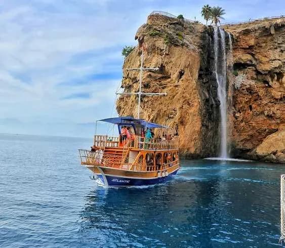 Ausflugsboot nähert sich einem Küstenwasserfall