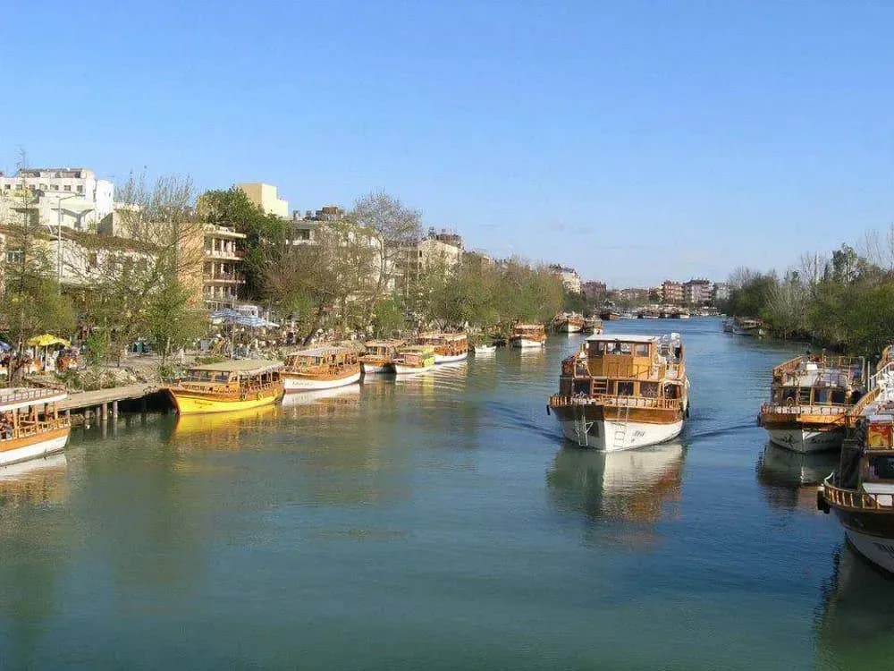 Boote liegen an einem von Bäumen gesäumten Flussufer