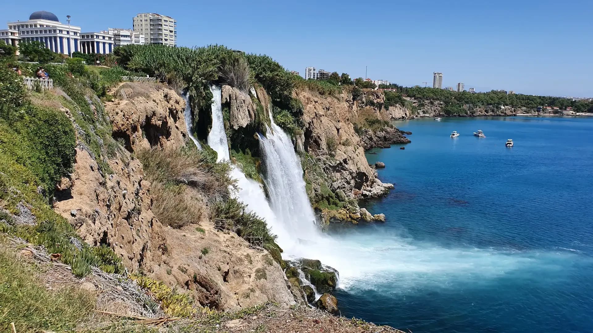 Wasserfall unter Stadtgebäuden auf einer Küstenklippe