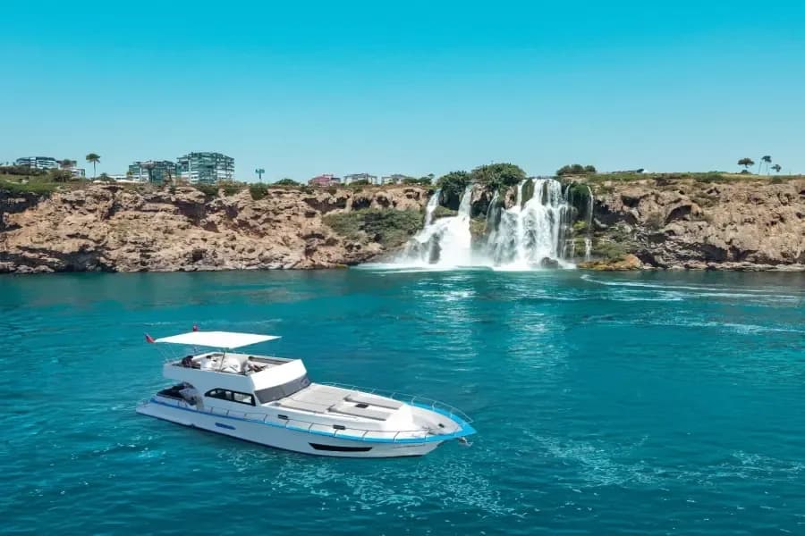 Motorboot neben einem Küstenwasserfall