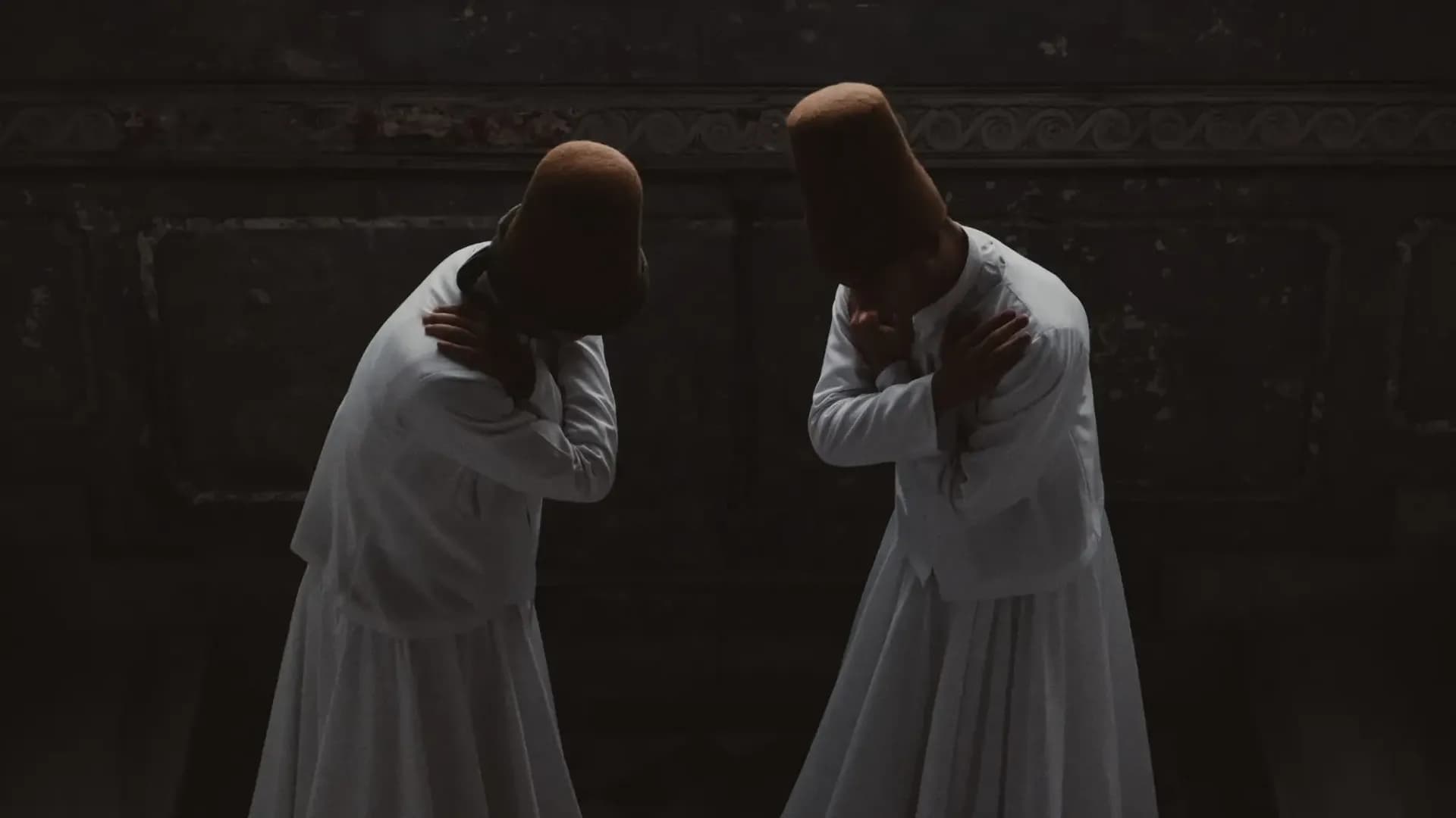 Two performers in white robes and tall hats